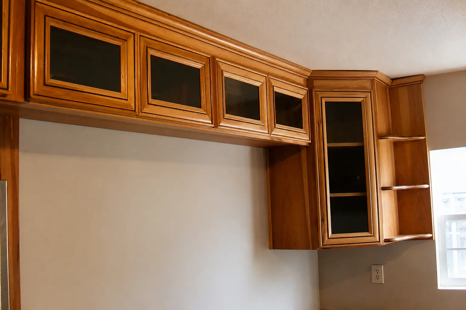 Maple upper cabinets with glass panel doors and curved corner shelving