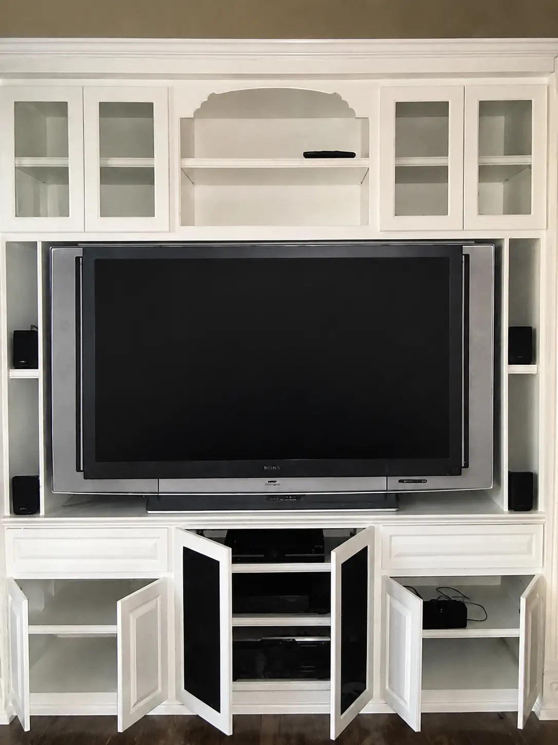 White custom entertainment center with glass upper cabinets