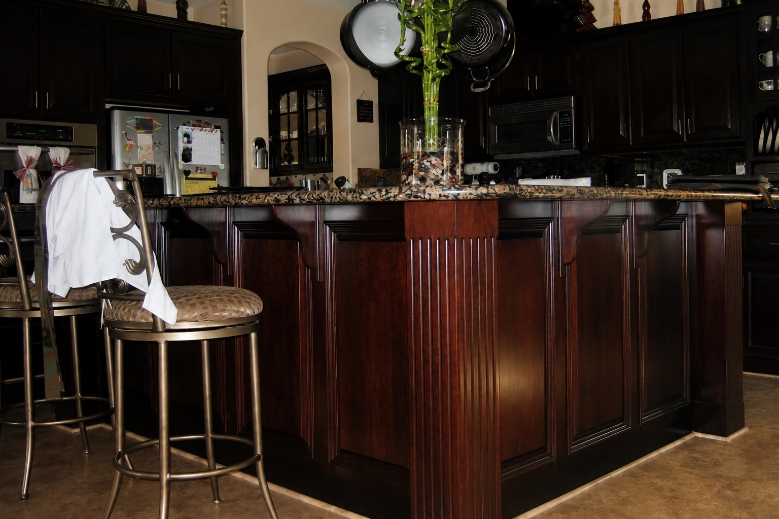 Dark cherry kitchen bar island with fluted column and granite countertop